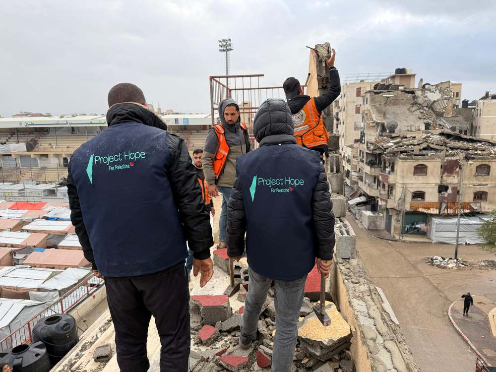 Volunteers and Civil Defense crews passing materials across rubble.