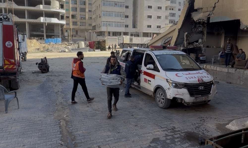 Civil Defense crews and Project Hope volunteers beside an ambulance amid destroyed buildings