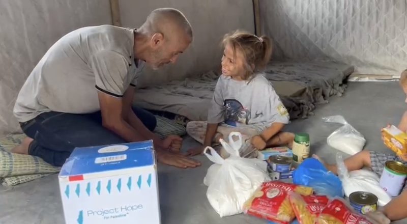 A Project Hope volunteer delivering food and supplies to a family with young children